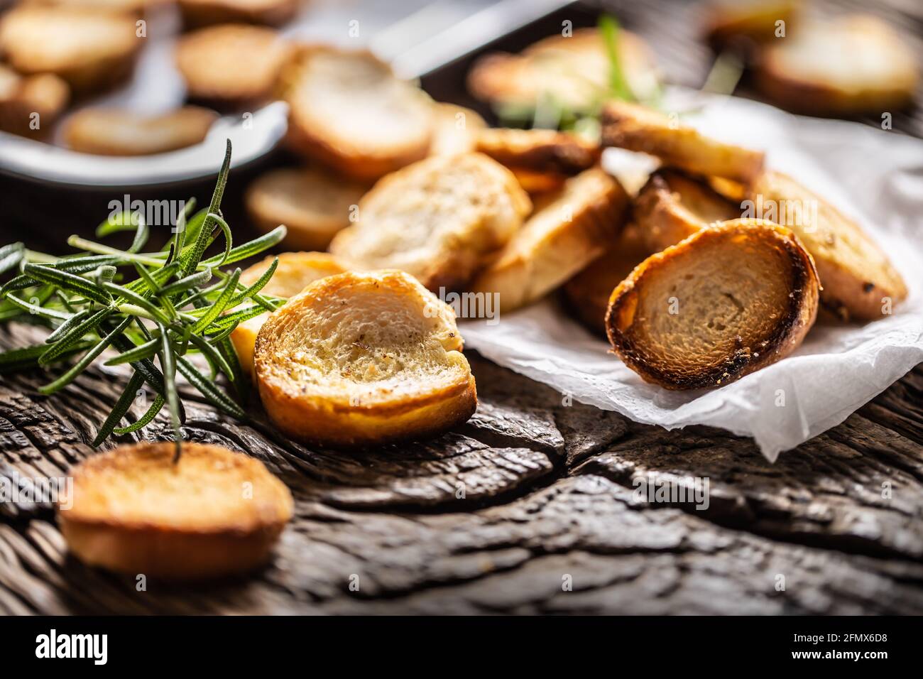 Crunchy and savory bake rolly with goldish color served in the paper with fresh green rosemary. Stock Photo