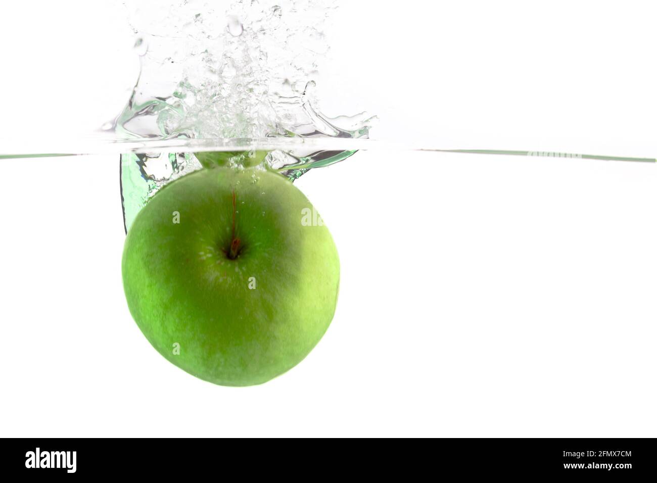 juicy green apple falls into the water on a white background, place under the text Stock Photo