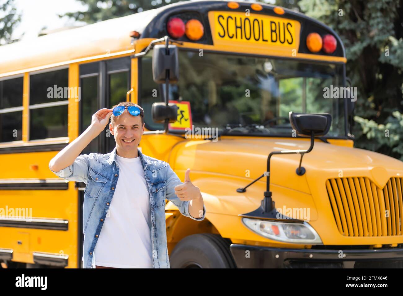 A happy male teacher near school bus Stock Photo - Alamy