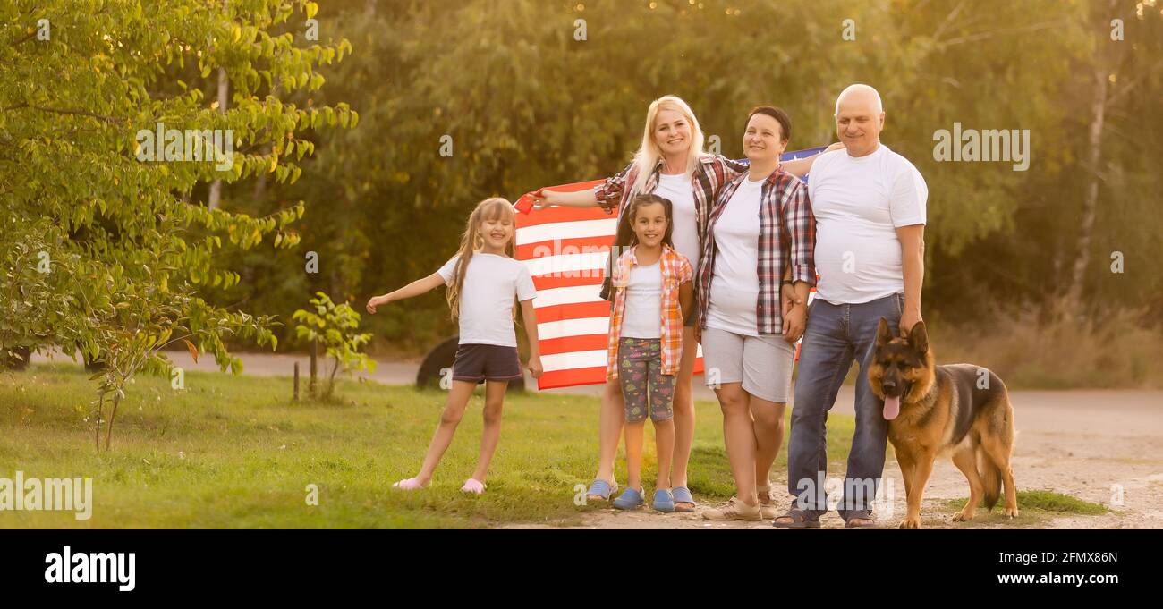 big family are walking walking american flags. Front view, american patriots on the park meadow. Stock Photo