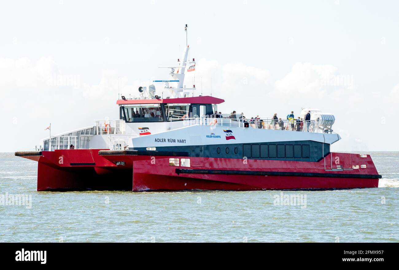 Norderney, Germany. 12th May, 2021. The catamaran MV 'Adler Rüm Hart' is underway in the Wadden Sea off the island of Norderney. AG Reederei Norden-Frisia is testing the use of a fast catamaran in passenger traffic on the route between Norddeich and Norderney. The three-day pilot project is initially intended to supplement the regular ferry service. Credit: Hauke-Christian Dittrich/dpa/Alamy Live News Stock Photo