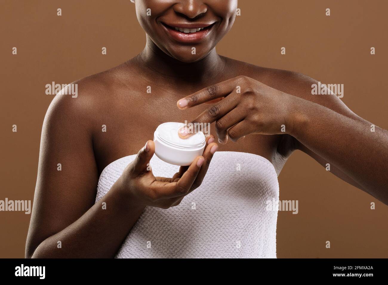 Skin Treatments. Smiling Black Lady Holding Open Jar With Moisturising Cream, Closeup Stock Photo