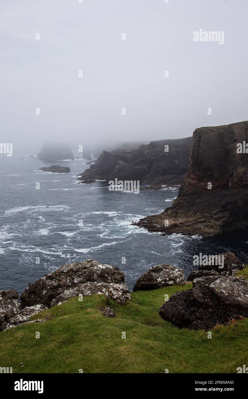 Misty coastal scene at Eshaness in Shetland on the western tip of Northmavine with spectacular coastal scenery, black cliffs and Atlantic Ocean Stock Photo