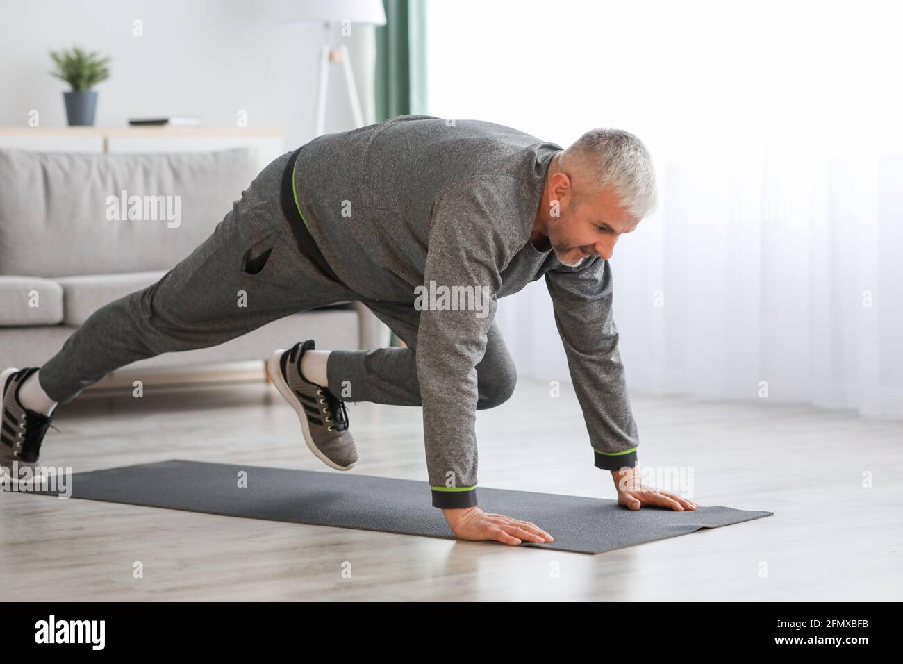 Athletic bearded senior man doing exercises at home Stock Photo