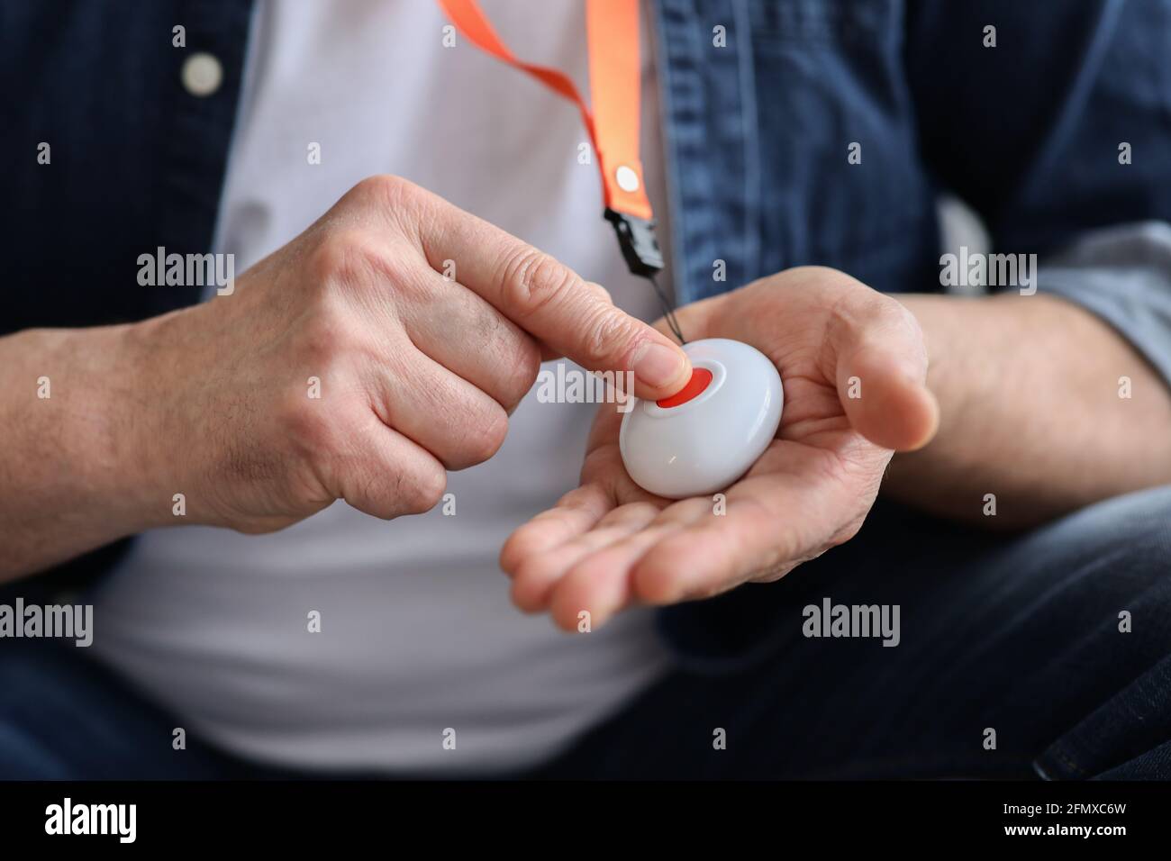 Hand pushing panic button on emergency equipment for elderly people Stock Photo
