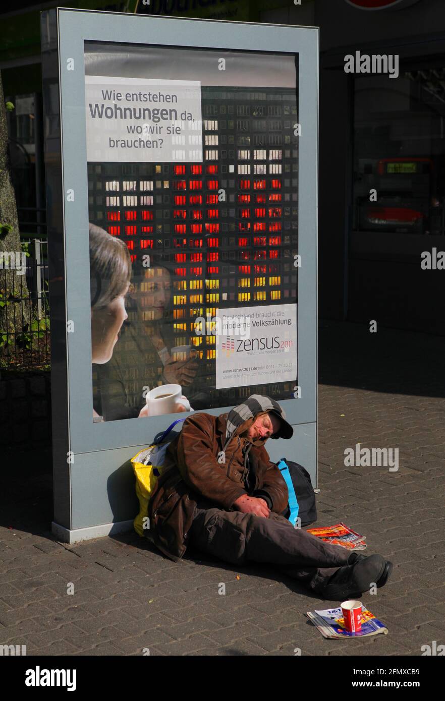 Genau vor einem Werbeplakat für die Volkszaehlung 2011 Zensus liegt ein Obdachloser nahe des Hauptbahnhofs in Duesseldorf. Das Plakat wirbt für die Vo Stock Photo