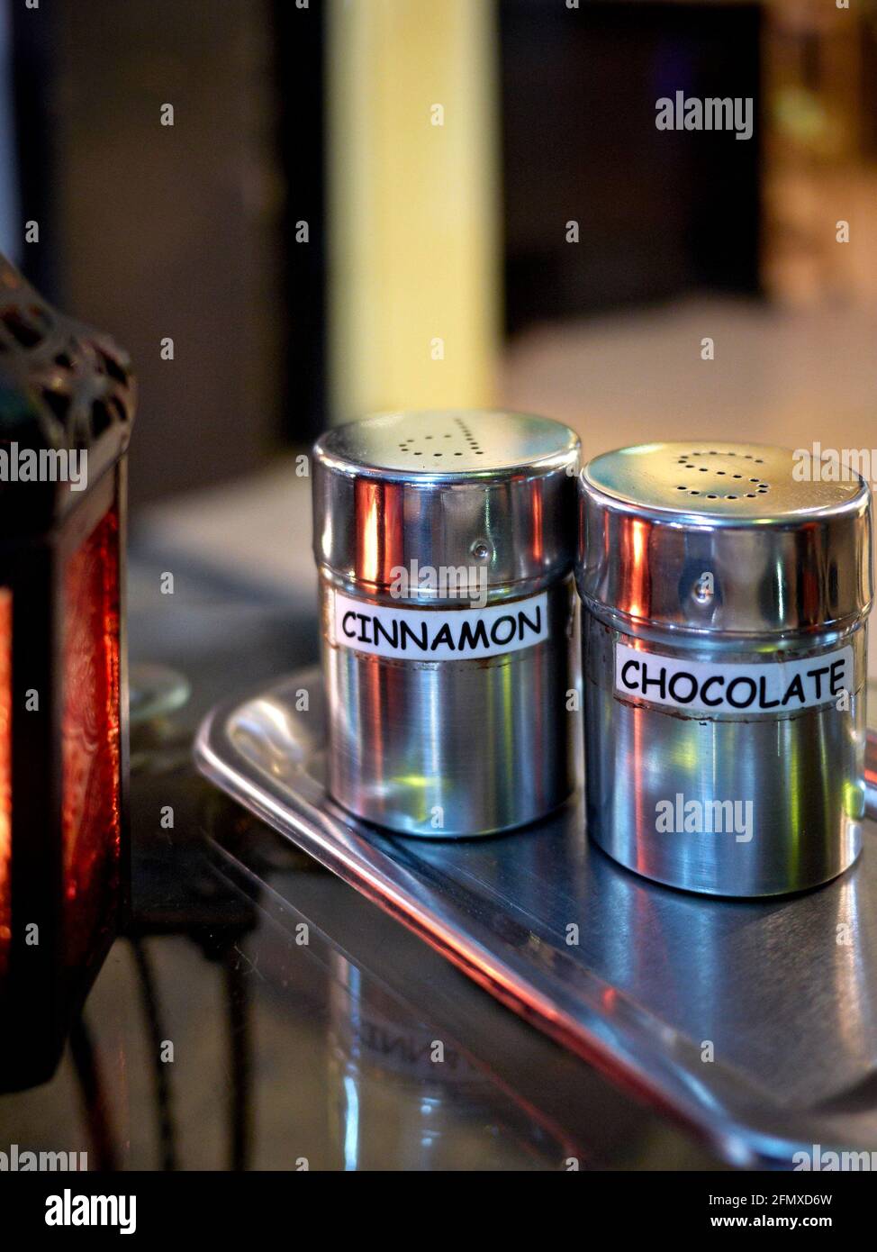 Stainless steel shakers containing cinnamon and chocolate primarily for coffee drinks Stock Photo