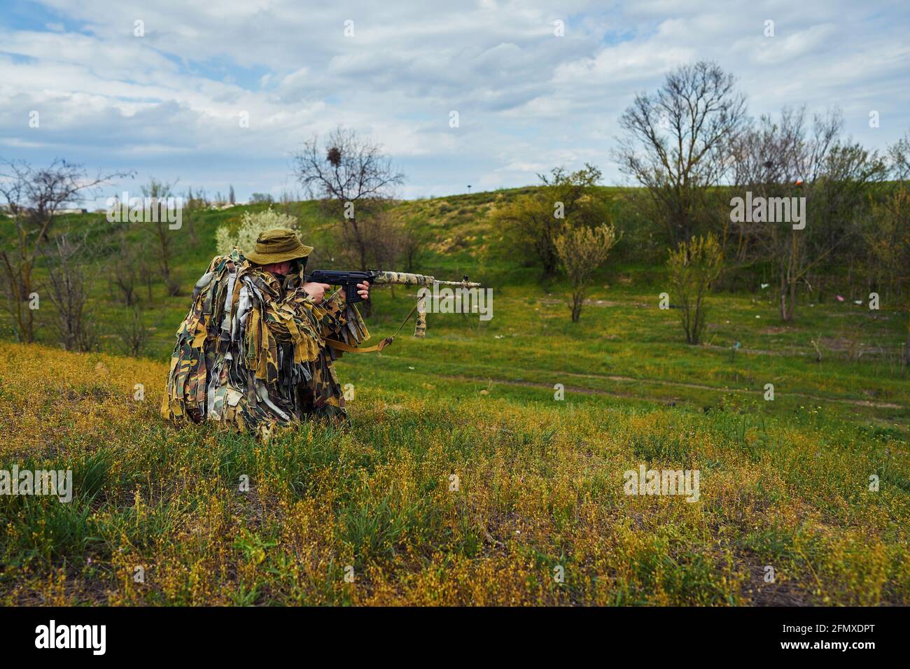 Airsoft player in camouflage military uniform holds a rifle in his ...