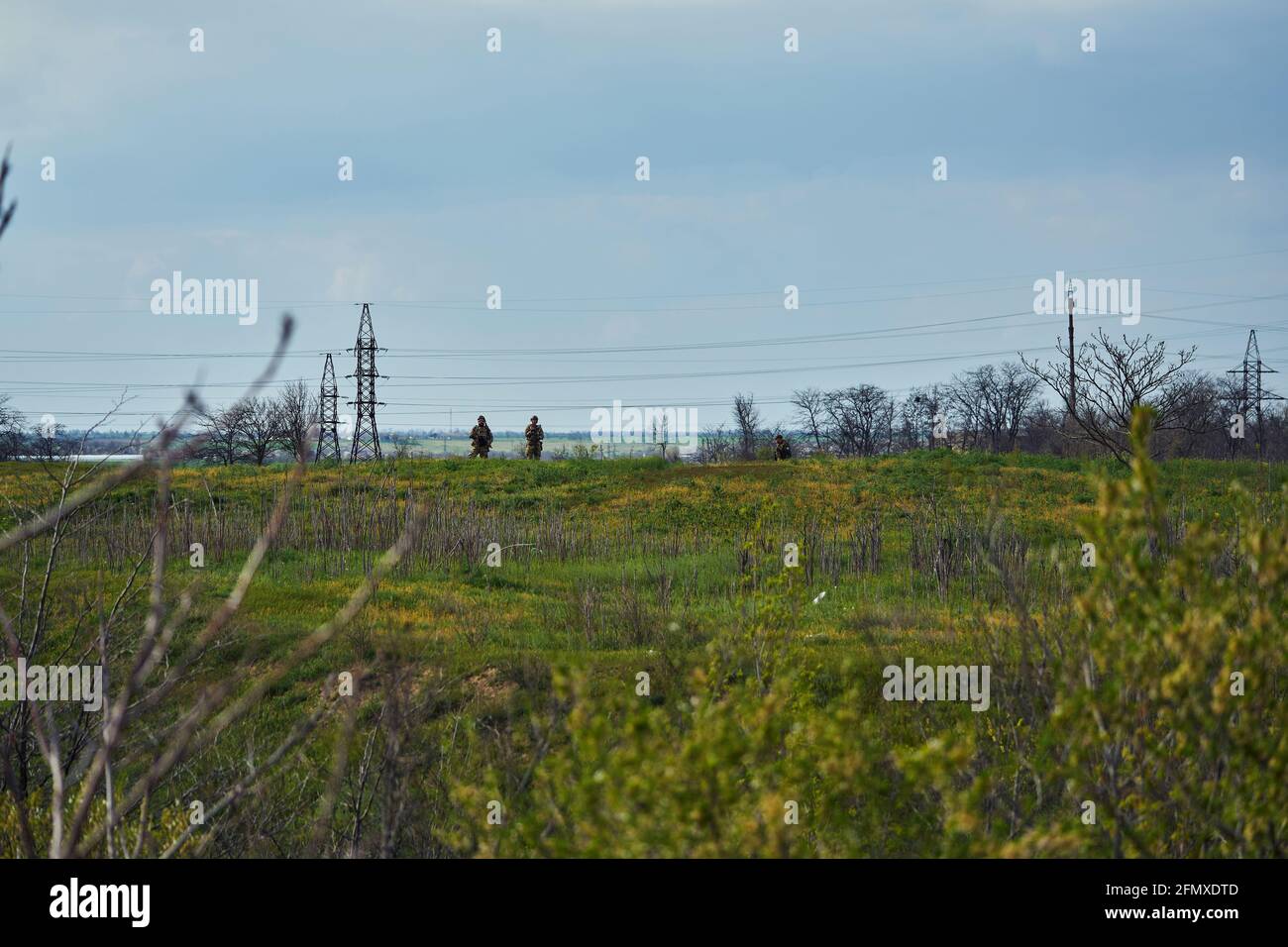 Two soldiers in the distance with weapons in their hands stand in the ...