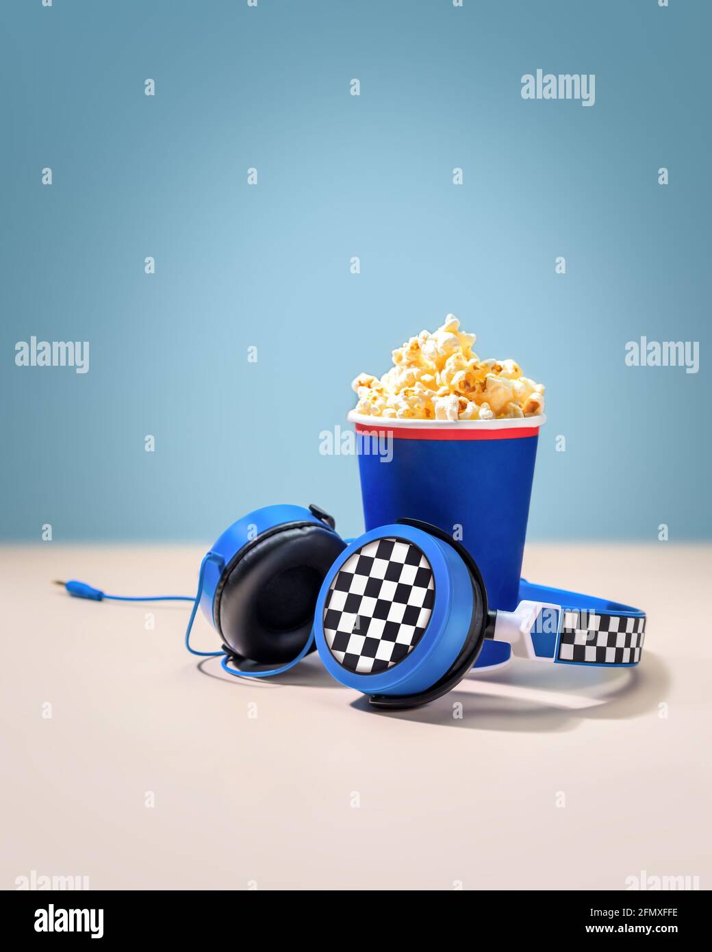 Composition with disposable cup with popcorn and headphones on a pink
