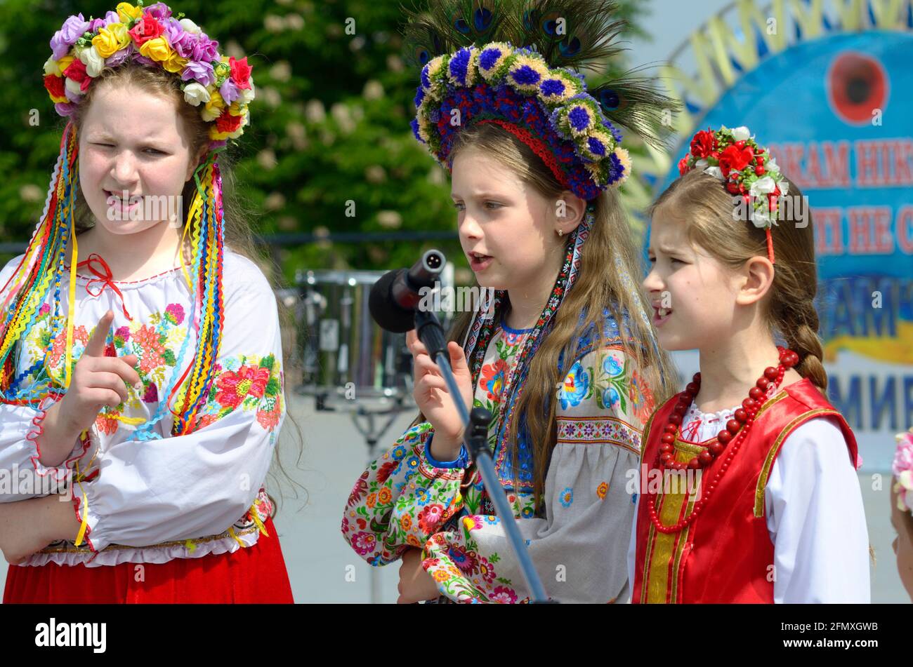 Three little girls in Ukrainian traditional embroidery costumes singing during concert devoted to the Remembrance Day. May 8, 2019. Kyiv, Ukraine Stock Photo