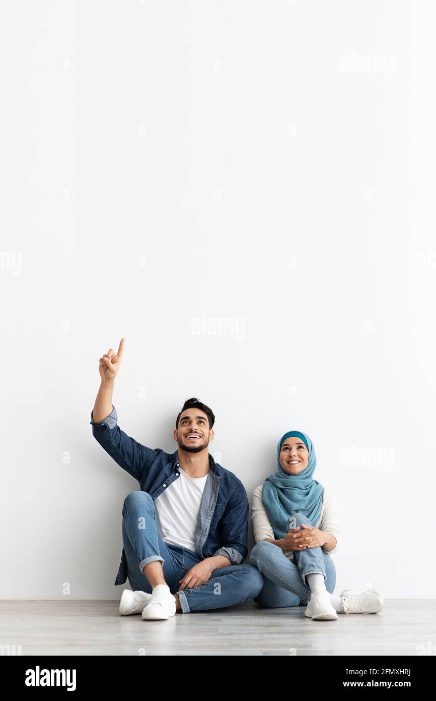 Cute muslim couple looking at empty space on white Stock Photo