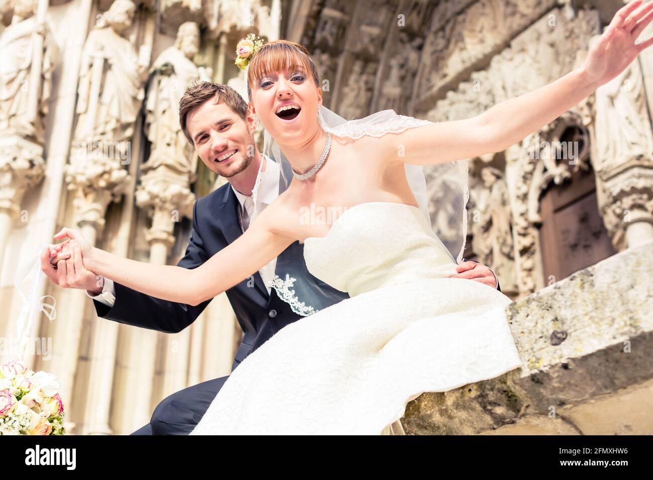 Close-up of excited married couple posing in front of ancient church Stock Photo