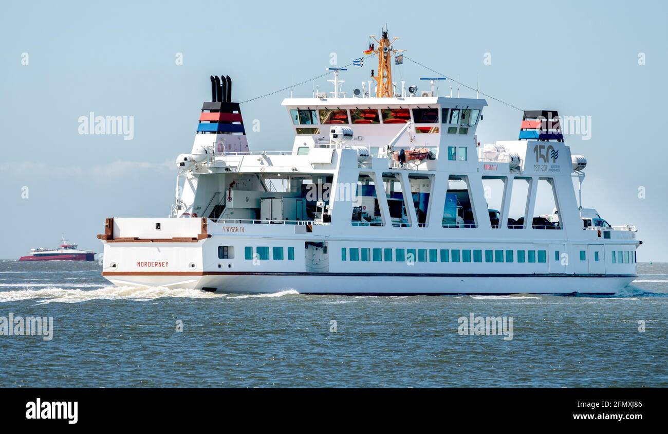 Norderney, Germany. 12th May, 2021. The ferry 'Frisia IV' is underway in the Wadden Sea off the island of Norderney, while in the background the catamaran MV 'Adler Rüm Hart' approaches the island. The AG Reederei Norden-Frisia is testing the use of a fast catamaran in passenger traffic on the route between Norddeich and Norderney. The three-day pilot project is initially intended to supplement the regular ferry service. Credit: Hauke-Christian Dittrich/dpa/Alamy Live News Stock Photo