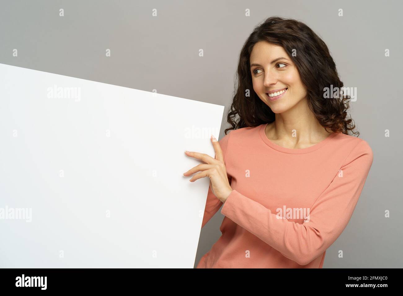 Young woman hold empty billboard look aside with happy smile to copy space at blank placard isolated Stock Photo