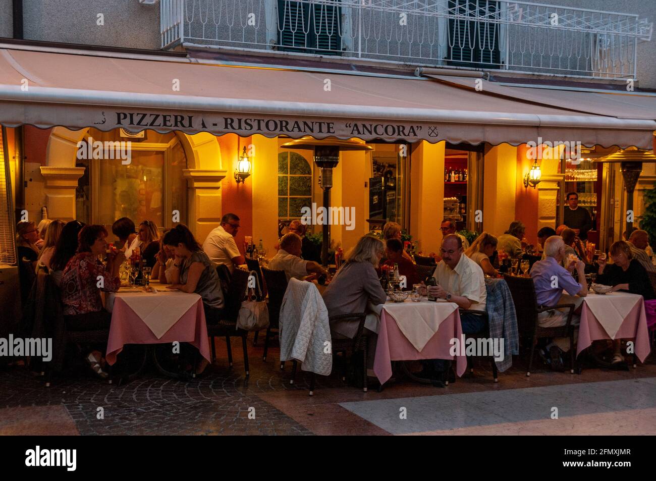 Tourists having dinner at some of the restaurants on Corso Umberto I in the early evening at Bardolino on the eastern shore of Lake Garda in the Venet Stock Photo