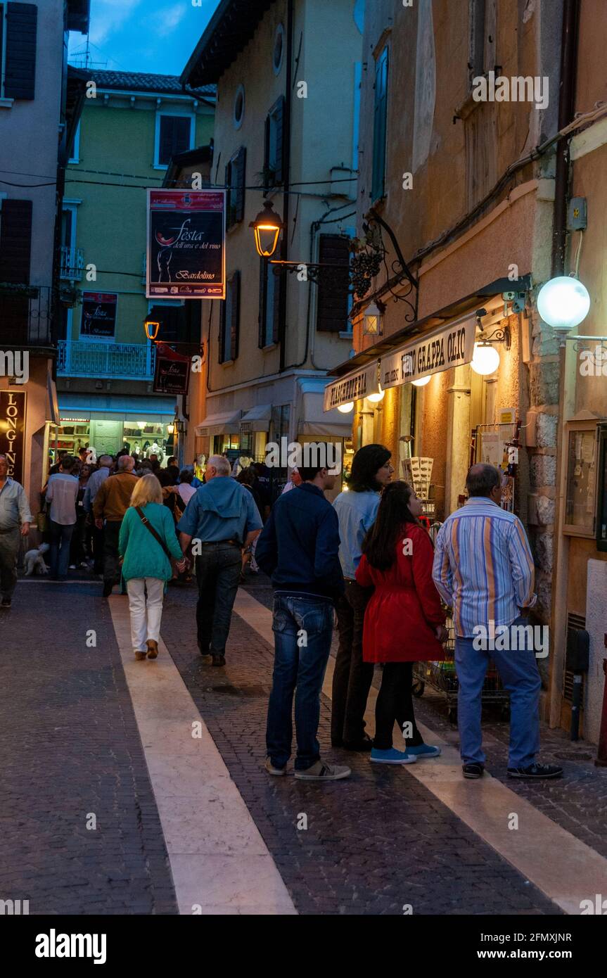 Tourists shopping in the early evening at Bardolino on the eastern shore of Lake Garda in the Veneto Region of northern Italy.   Many of these shops c Stock Photo