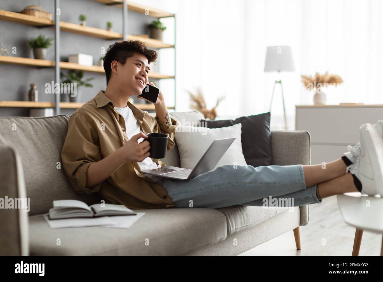 Smiling asian man working and talking on phone at home Stock Photo