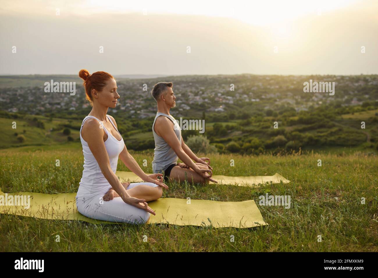 Man and woman meditating in countryside at sunset Stock Photo