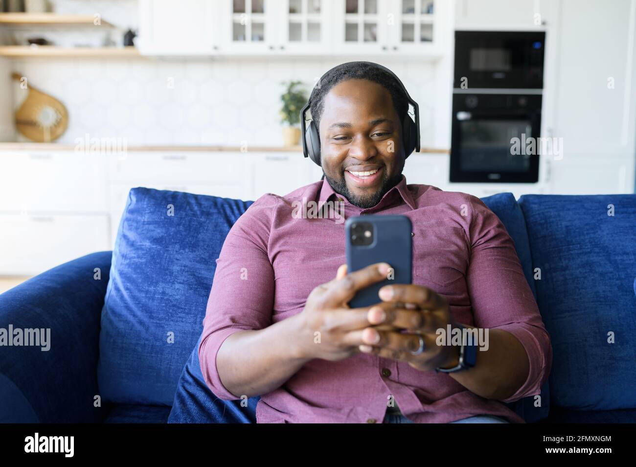 Hilarious African American man in headphones spends leisure with