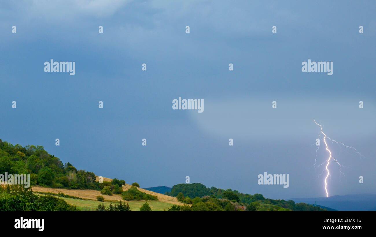 Thunderstorm with lightning over the hilly landscape Stock Photo