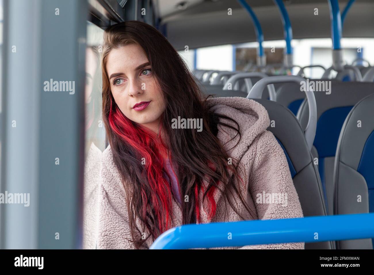 A young woman rides a bus and stares serenely out the window Stock Photo