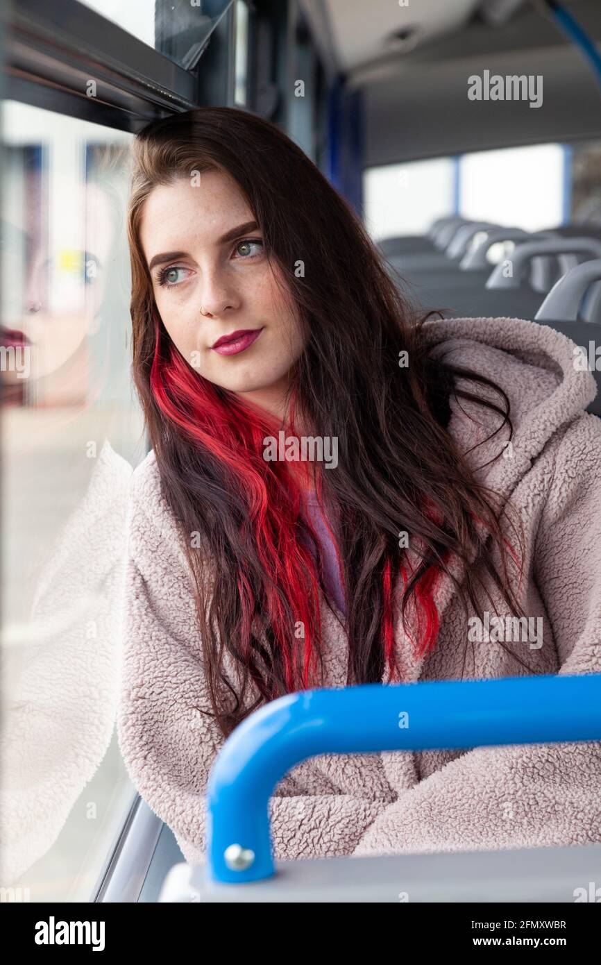 A young woman rides a bus and stares serenely out the window Stock Photo