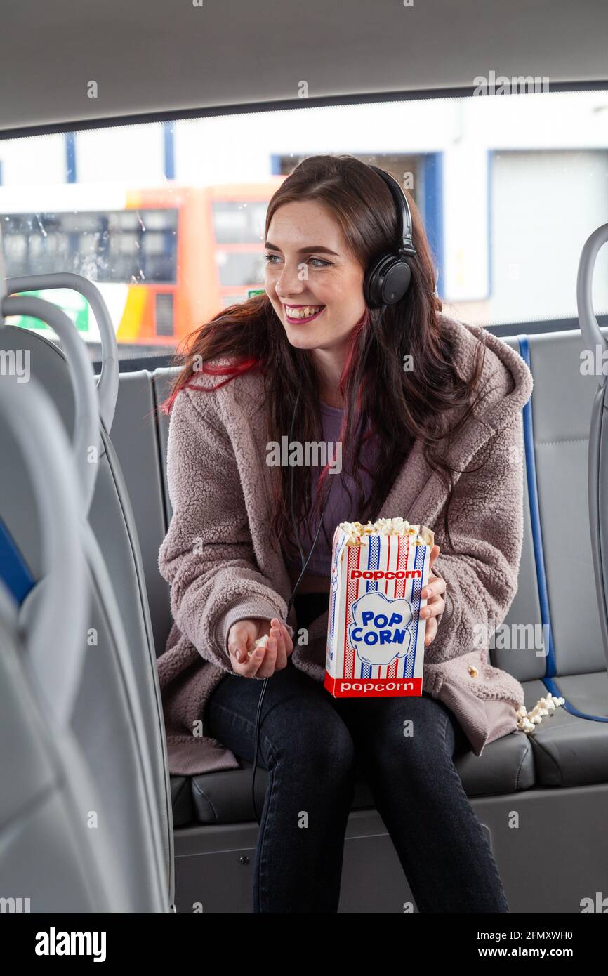 A young woman eating popcorn on the back seat of a bus Stock Photo Alamy