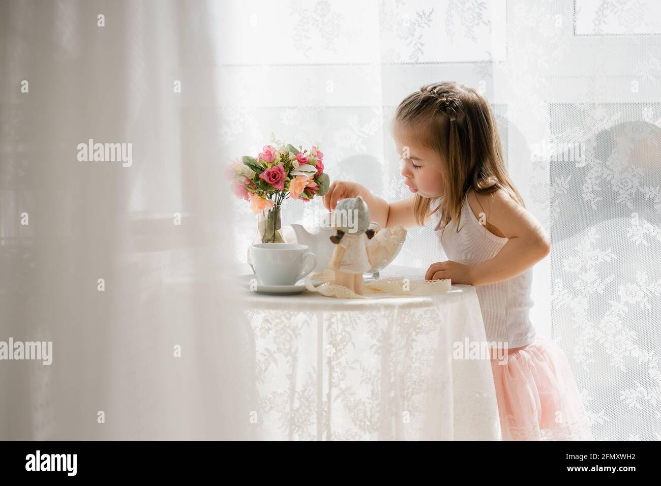 little girl in a pink skirt have breakfast, beautiful sunlight at home Stock Photo