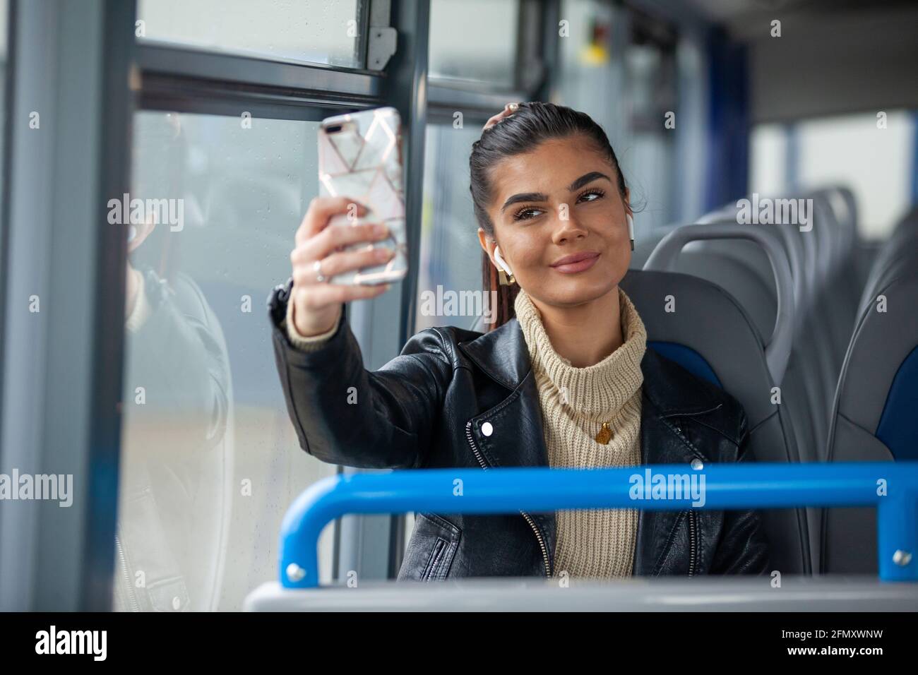 A woman taking a seflie of herself on a bus Stock Photo