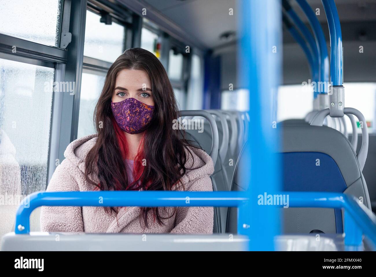 A young woman sitting on a bus looking towards camera Stock Photo