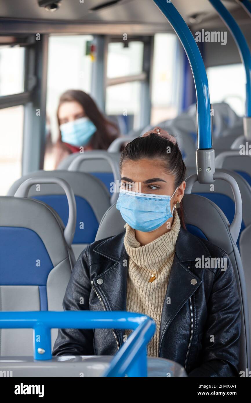 A woman travelling on a bus wearing a face mask, with another woman