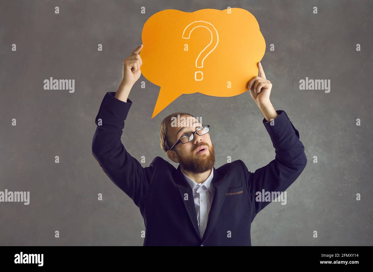 Sceptical businessman in suit and glasses holding speech bubble with question mark Stock Photo