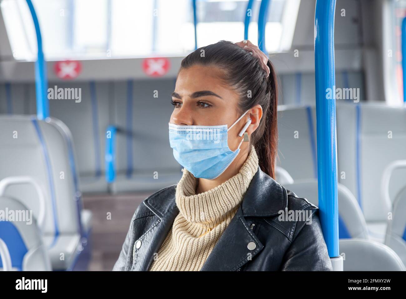 A woman travelling on public transport wearing her face mask under her nose Stock Photo
