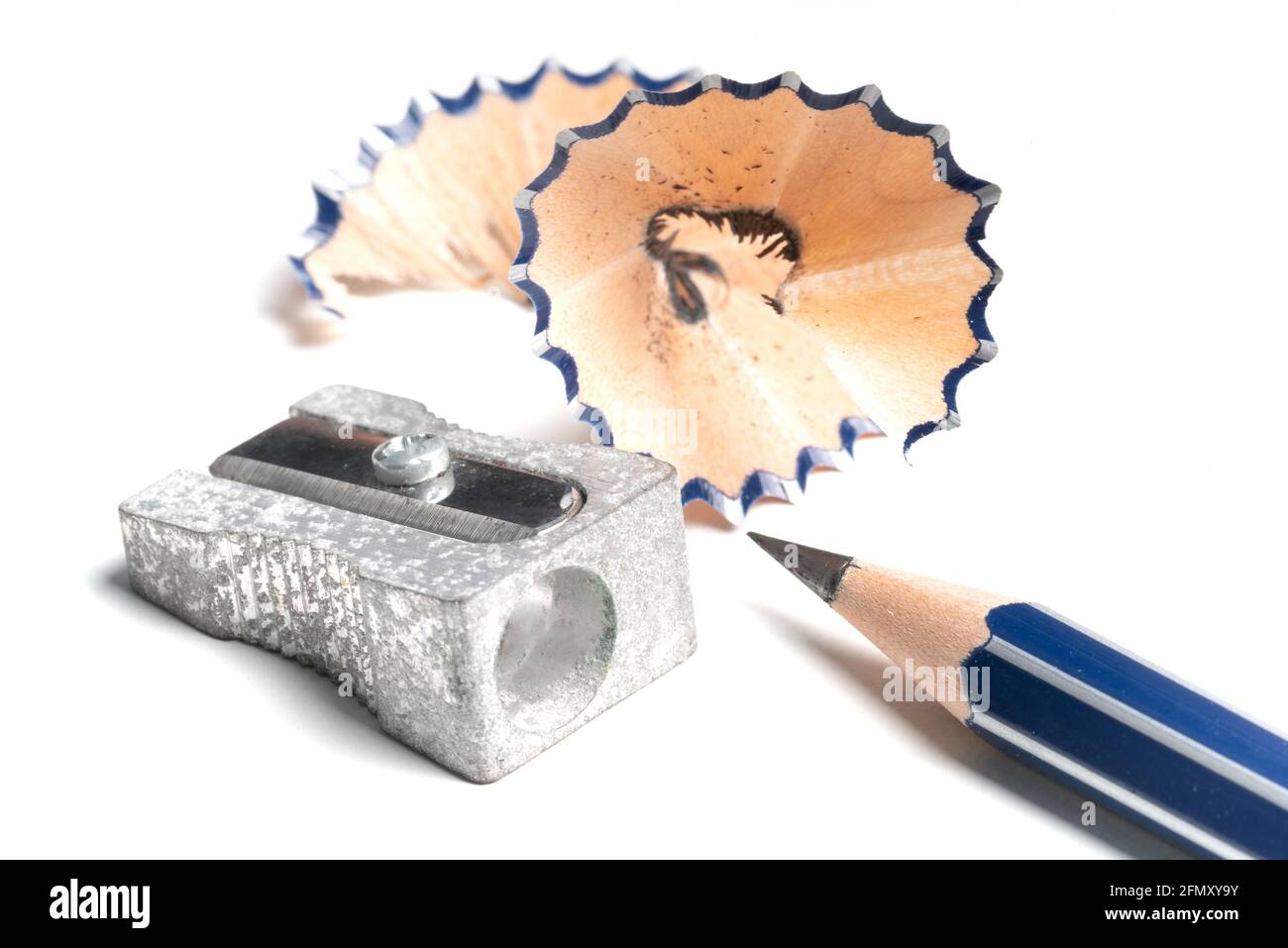 high angle view of sharp pencil, pencil sharpener and shavings on white desk Stock Photo