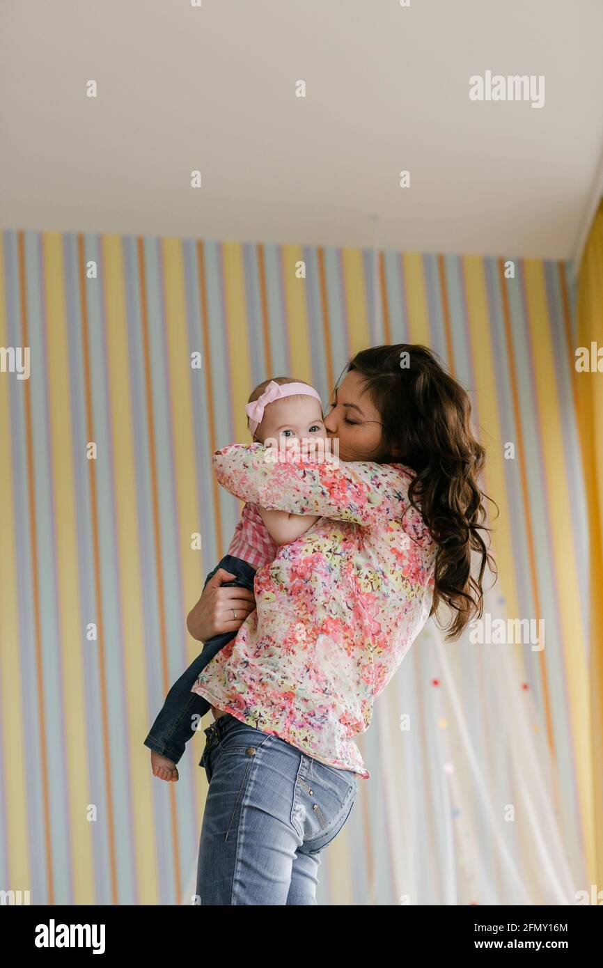 family, childhood and parenthood concept - happy little baby learning to walk with mother help at home Stock Photo