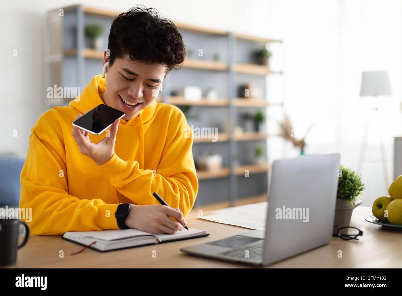 Asian guy using voice assistant on cellphone Stock Photo