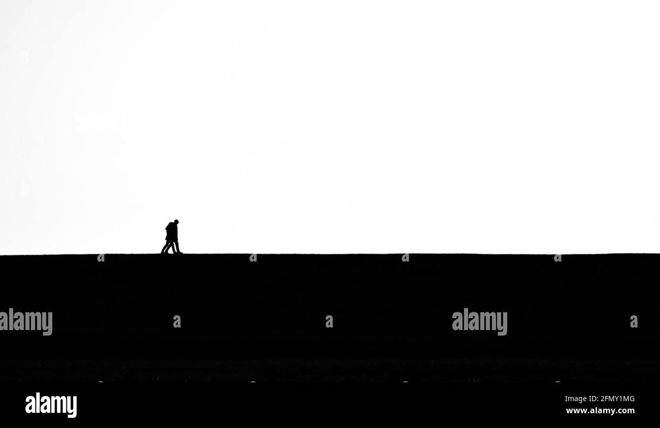 Black And White, Monochrome Of Two People Walking Together On The Skyline horizon Minimalist Style Uk Stock Photo