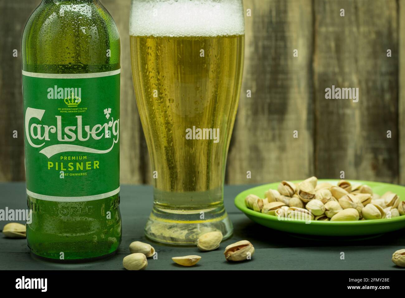 Warsaw, Poland - April 26, 2021: Cool Carlsberg beer in a glass bottle on a wooden background. Carlsberg beer bottle with water drops. Copy space for Stock Photo