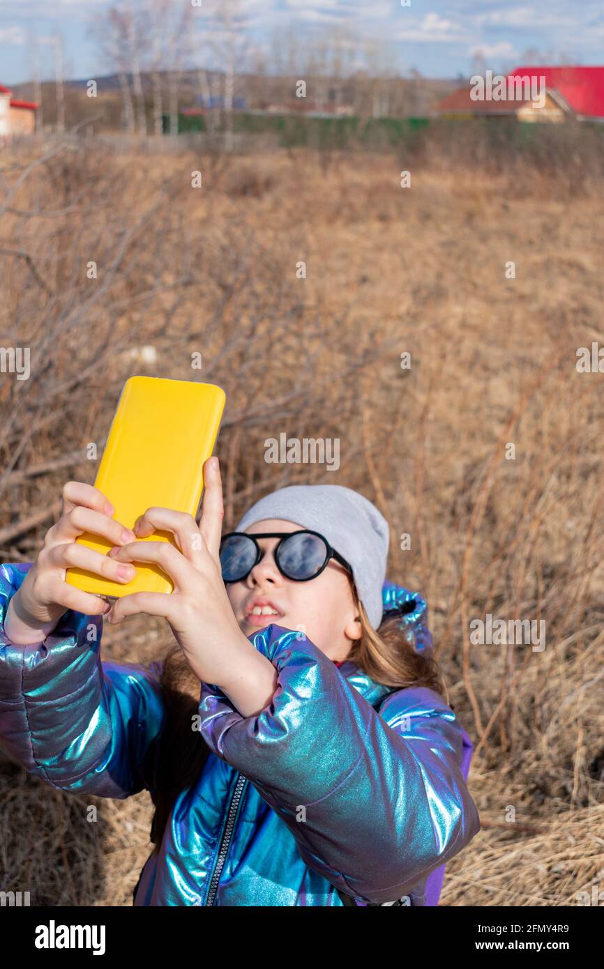 Teenage girl looks the phone and takes selfie. Children use technology concept. Stock Photo