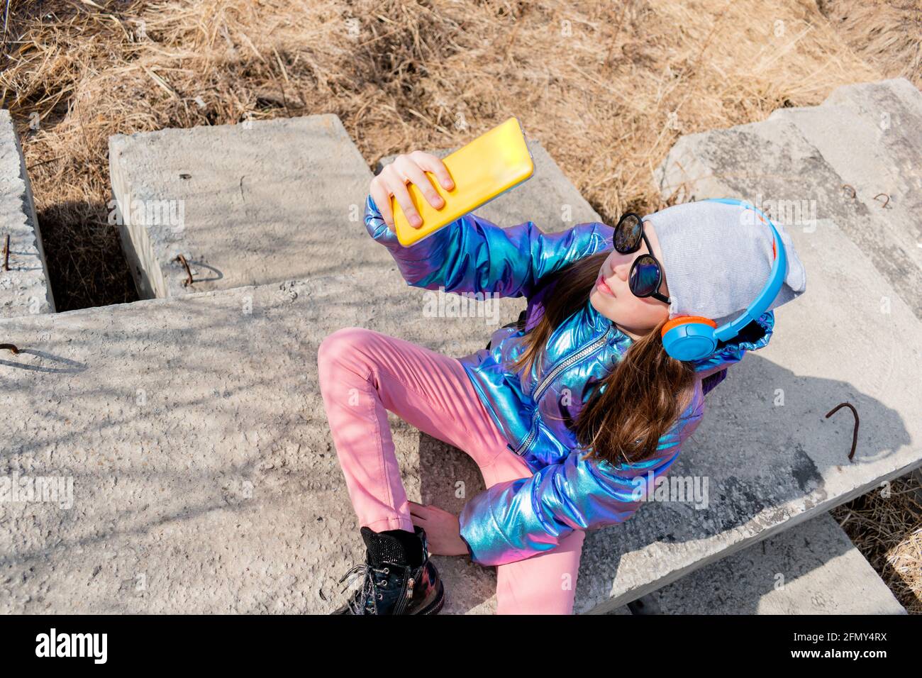 Teenage girl looks the phone and takes selfie. Children use technology concept. Stock Photo