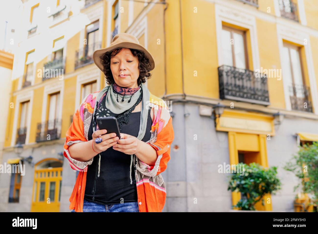 modern middle-aged woman walking and using her smartphone Stock Photo