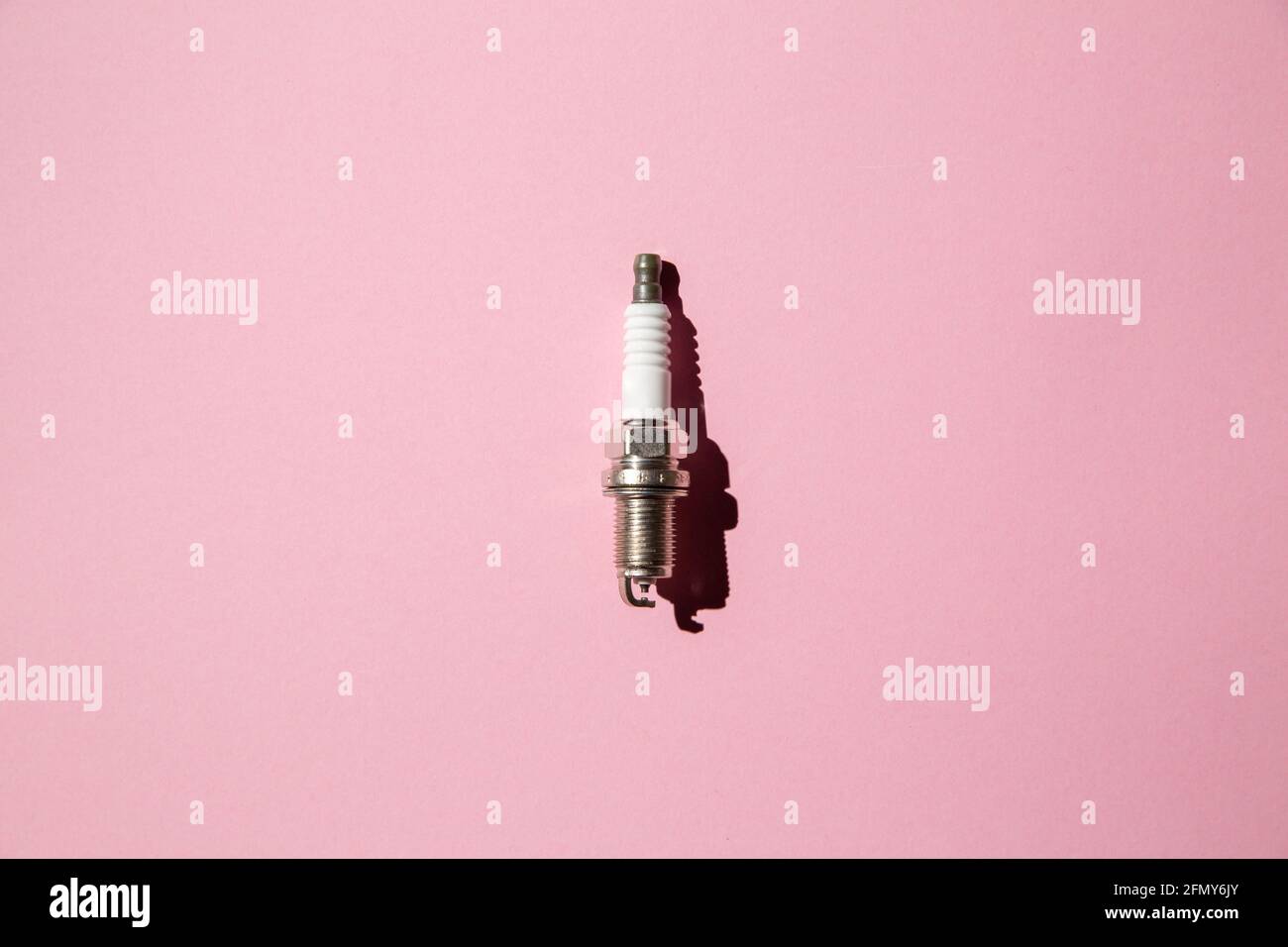 Spark plug. Car candle lies against a pink background. Auto engine electrician. Copy space. Flat lay Stock Photo