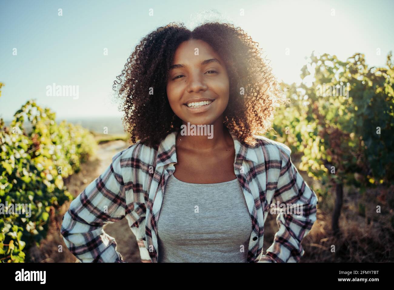 Beautiful mixed race female farmer smiling while standing in vineyard of farm Stock Photo