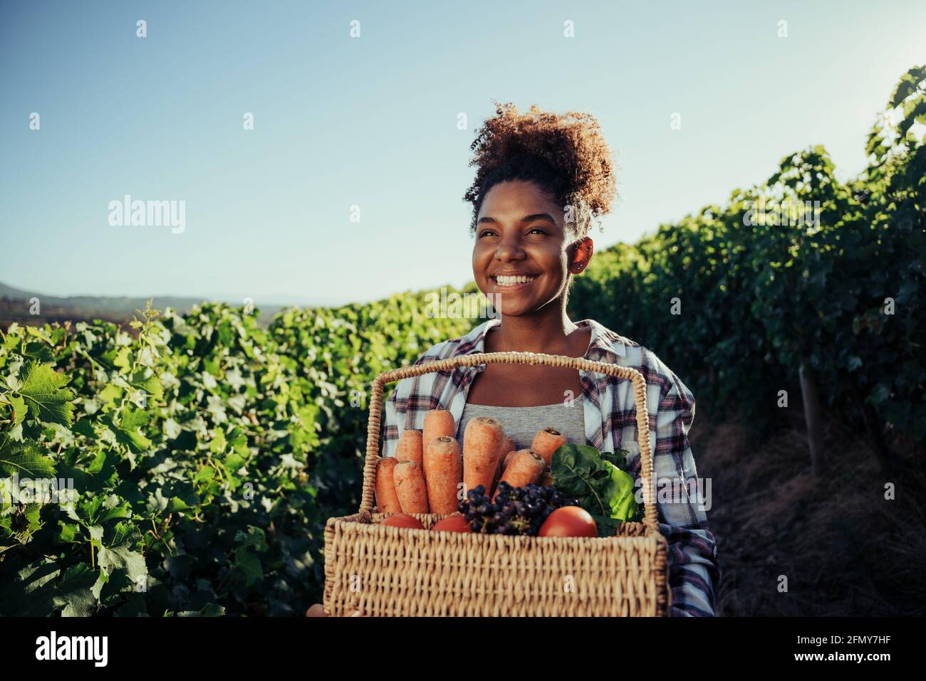 Mixed race female farmer feeling happy after successful day of vegetable harvest Stock Photo