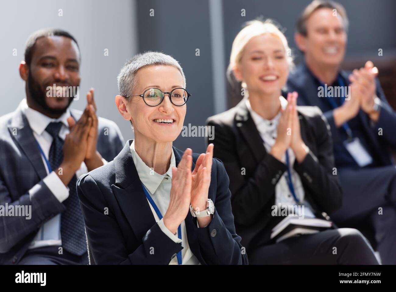 selective focus of mature businesswoman applauding during seminar near  interracial colleagues Stock Photo - Alamy