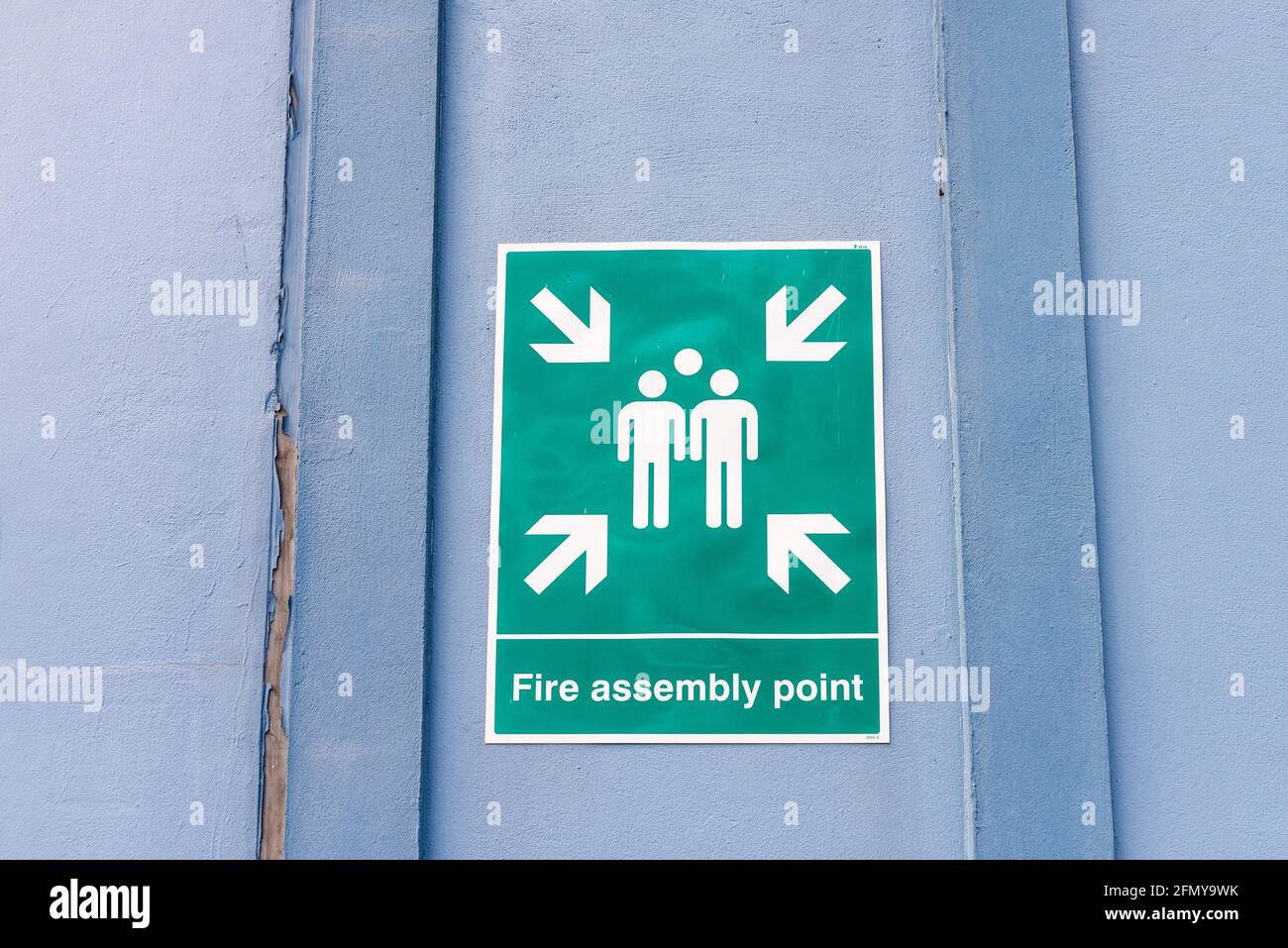 Green 'Fire Assembly Point' sign on a factory door Stock Photo
