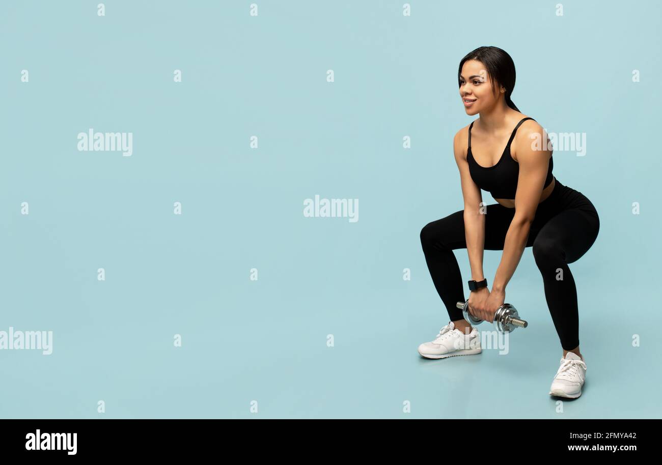 Training concept. Fit african american woman doing deep squats with dumbbell on blue background with free space Stock Photo Alamy