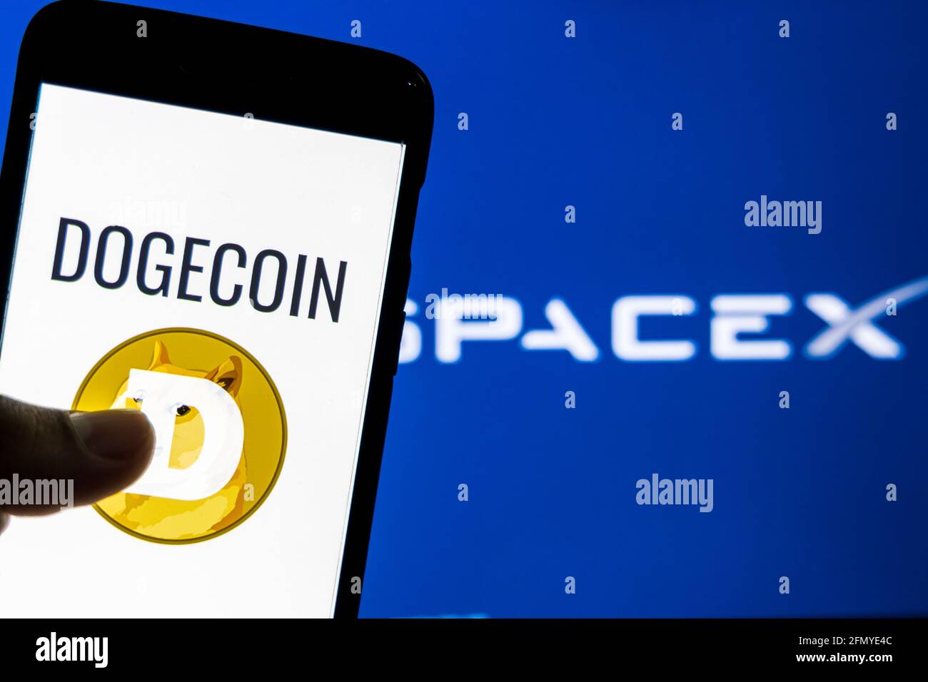 Dogecoin logo on a smartphone against SpaceX logo in the background. SpaceX accepts Dogecoin as payment to launch ‘DOG Stock Photo