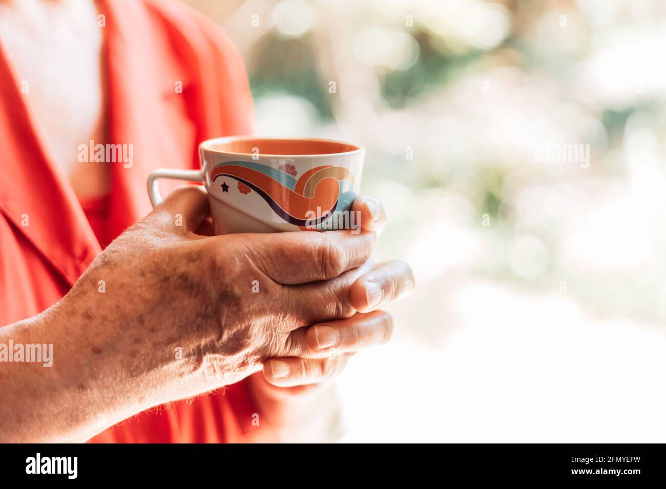 Old woman hands holding a cup of coffee. Copy space Stock Photo
